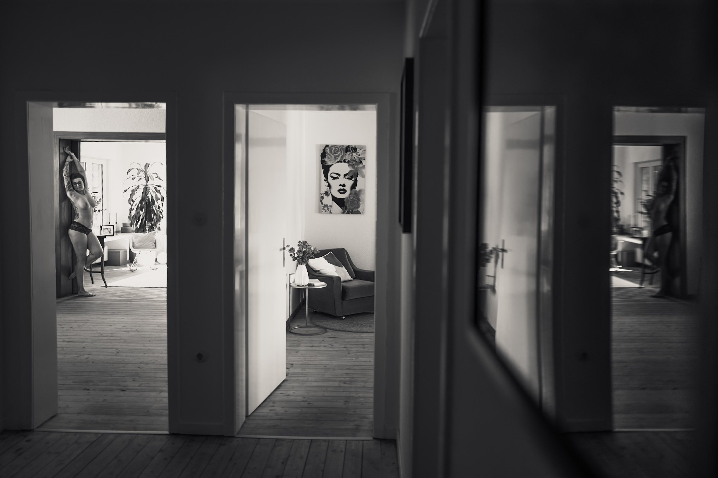 Julia im Türrahmen ihrer Wohnung mit Spiegelung im Flur, Schwarzweiß