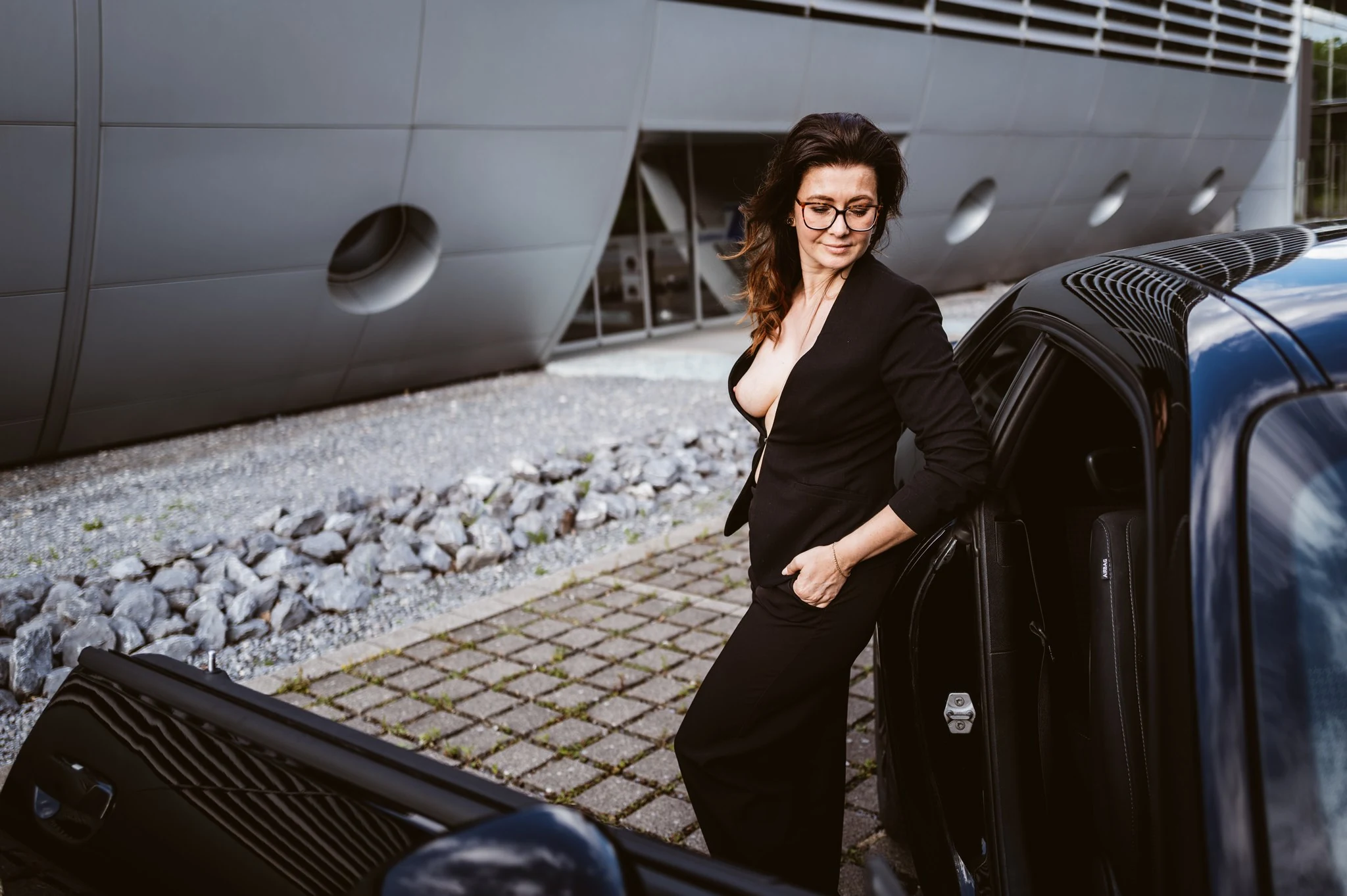 Julia im schwarzen Anzug neben dem Auto