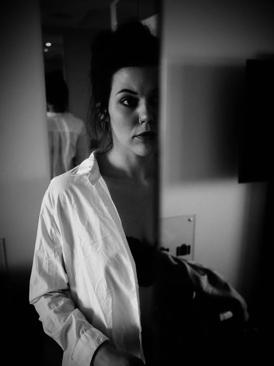 Der Anfang im Hotel: eine Frau im weißen Hemd, im Spiegel fotografiert.