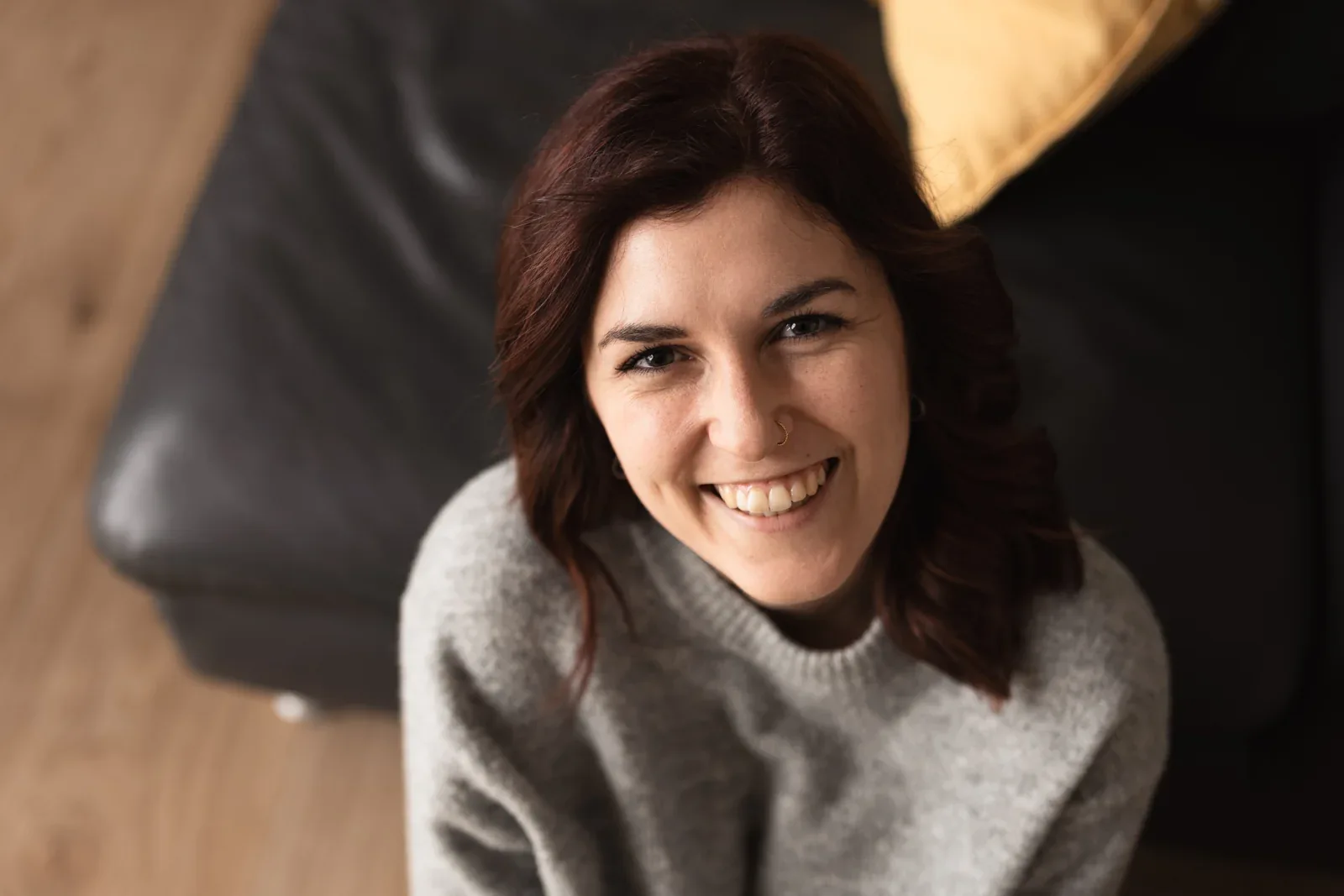 Eine Frau lacht im großen Pullover.