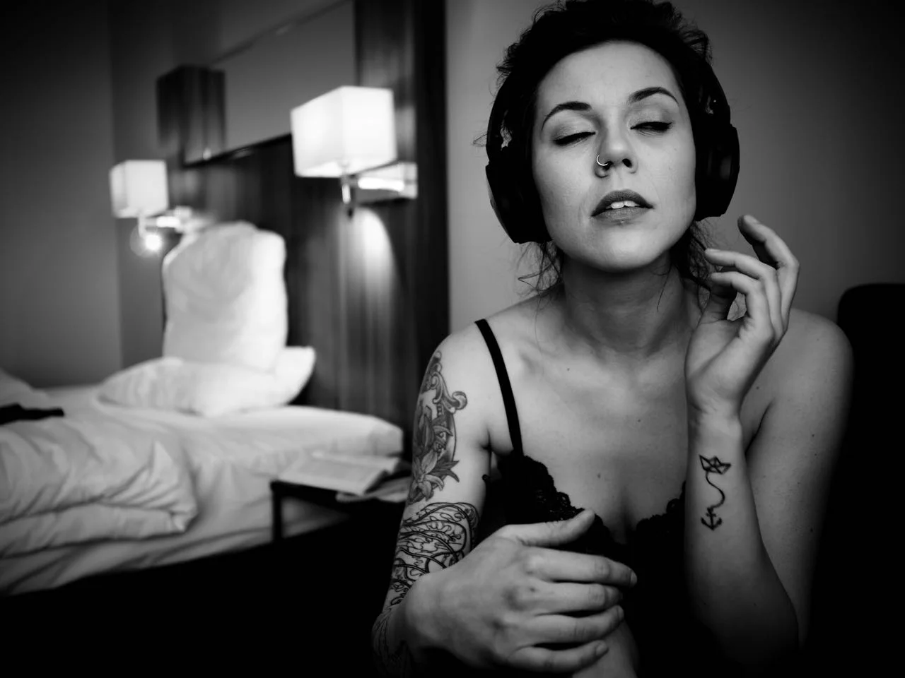 Eine Frau im Body hört mit geschlossenen Augen Musik über Kopfhörer.