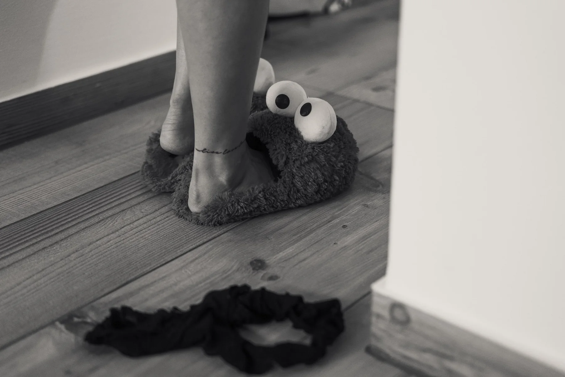 Krümelmonster-Hausschuhe auf einem Holzboden.