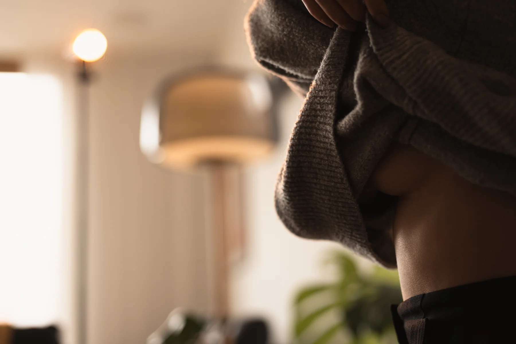 Ein großer Strickpullover und eine Hand im warmen Licht.
